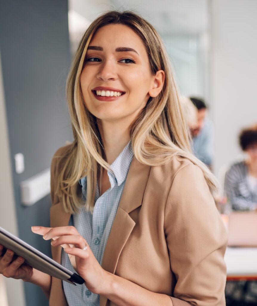 Smiling confident business leader looking at camera and standing in an office at team meeting